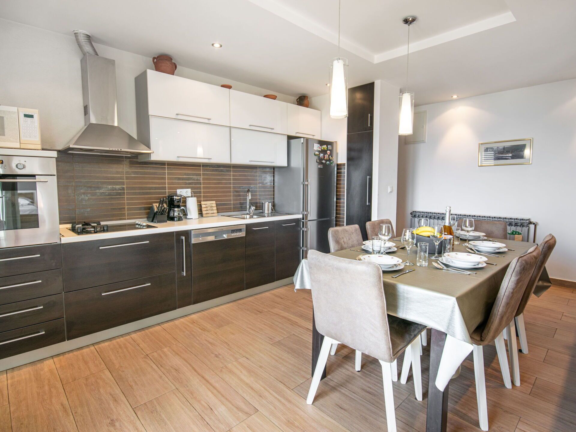 Een moderne keuken met roestvrijstalen apparatuur, een eethoek met een tafel voor vier personen, en een groot raam dat voor natuurlijk licht zorgt.