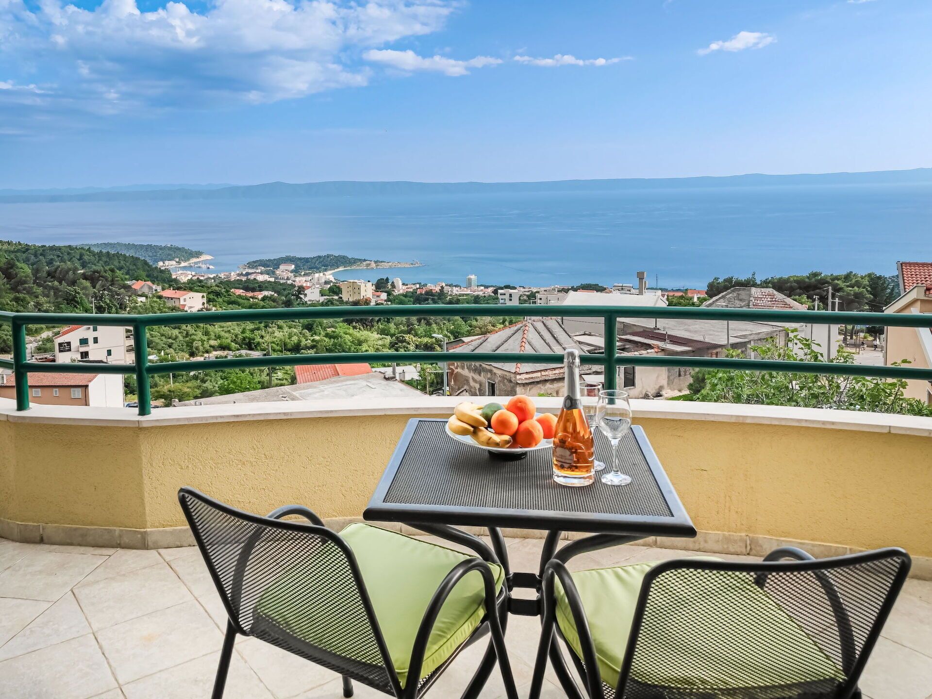 Een balkon met een tafel voor twee personen, met uitzicht op de kust.