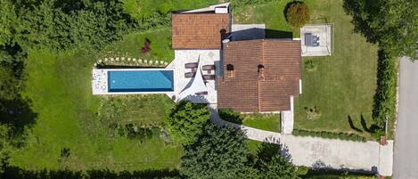 Luchtbeeld van een huis met een zwembad, tuin en oprit.