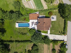 Vista aérea de una casa con piscina, jardín y entrada para vehículos.