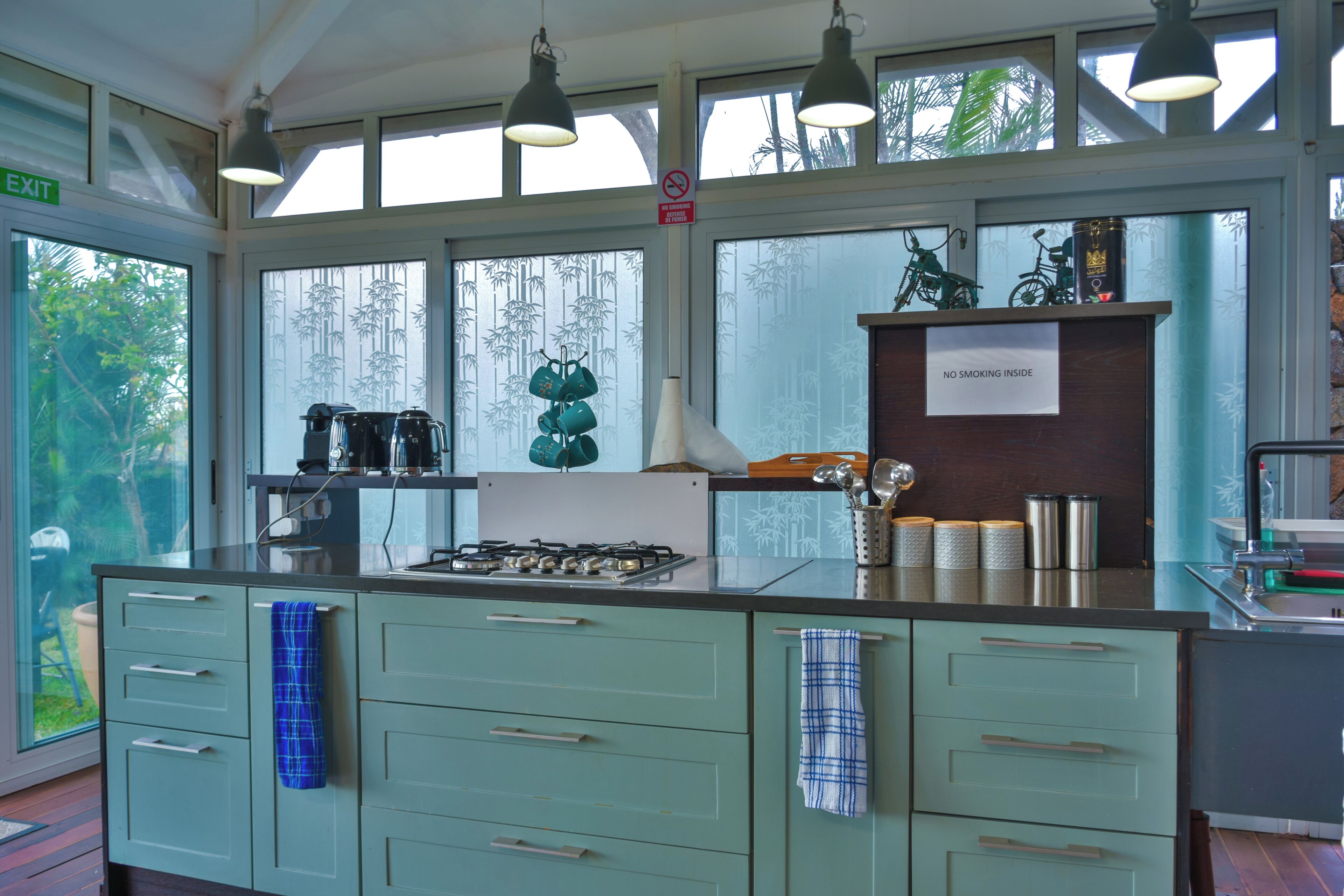 A kitchen with a gas stove, hanging kitchen towels, and a 'No Smoking Inside' sign.