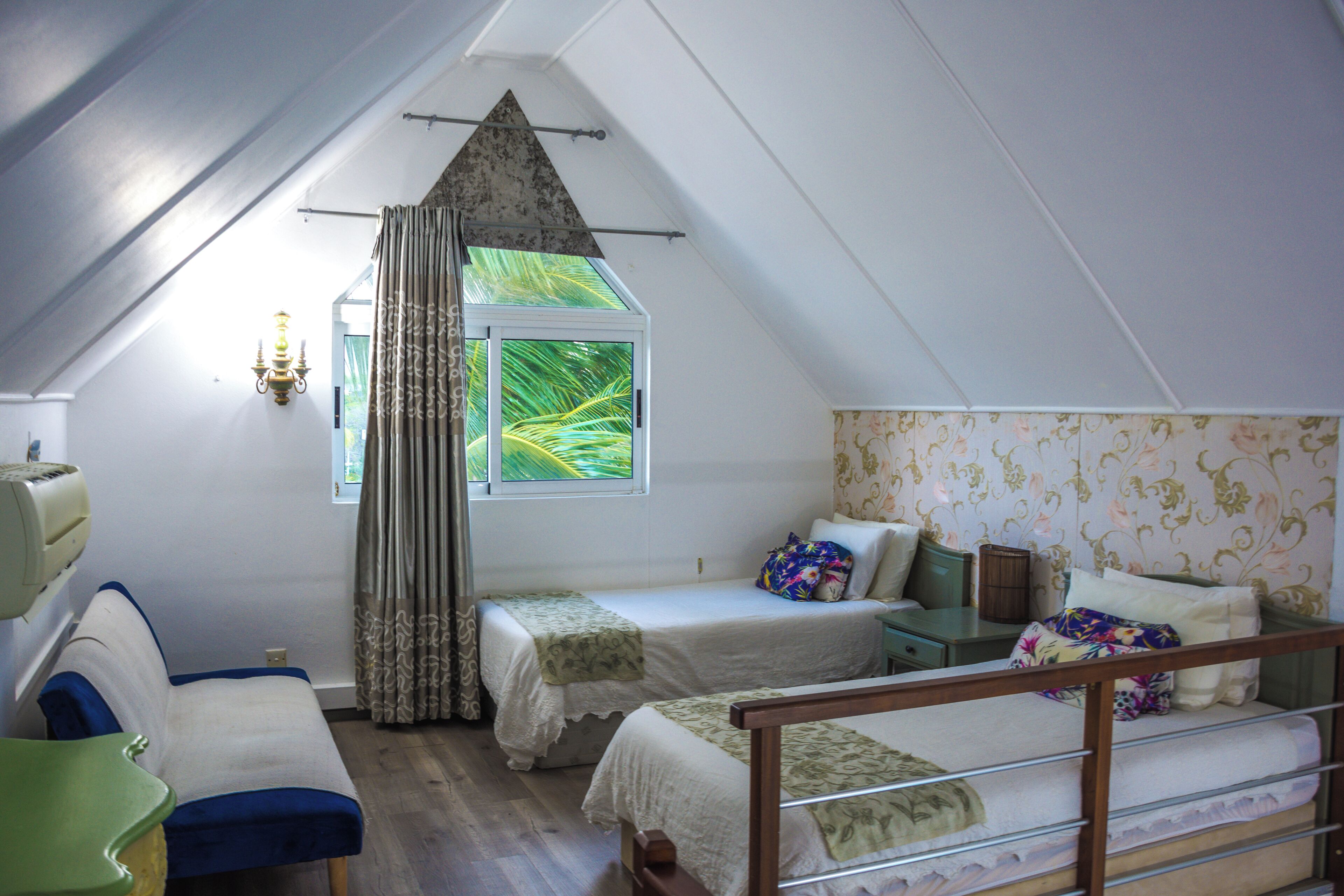 Un dormitorio con dos camas, una ventana con cortinas, una mesita de noche y una lámpara.