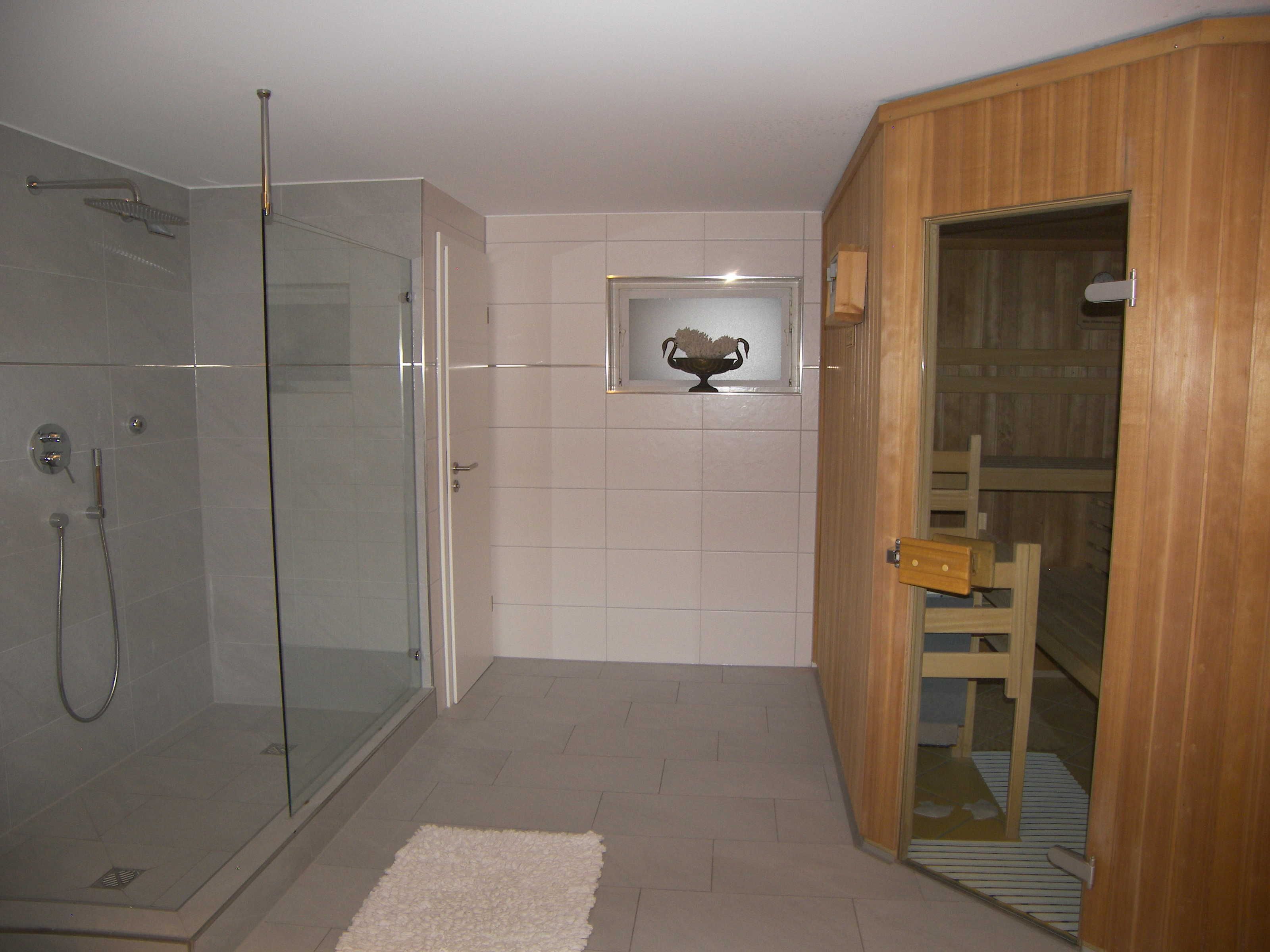 Une salle de bain moderne avec une douche à parois de verre, une porte en bois et une petite étagère décorative.