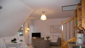 A cozy living room with a dining area, a kitchen, and a staircase.