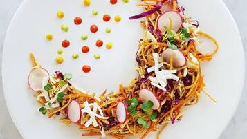 A white plate with a colorful salad, including shredded vegetables, radishes, and sprouts.