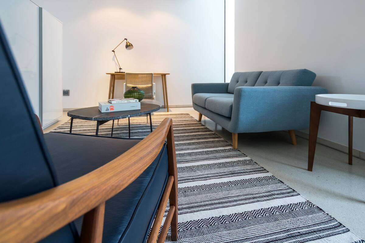 A modern living room with a sofa, a coffee table, a lamp, and a patterned rug.