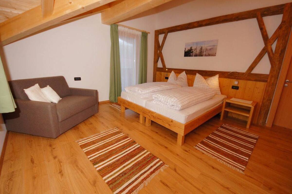 Ein Schlafzimmer mit einem hölzernen Bett, einem Sofa und einer Holzzahlung.