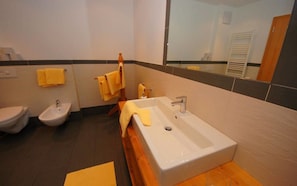 Une salle de bain avec un lavabo blanc, un bidet et deux serviettes jaunes.