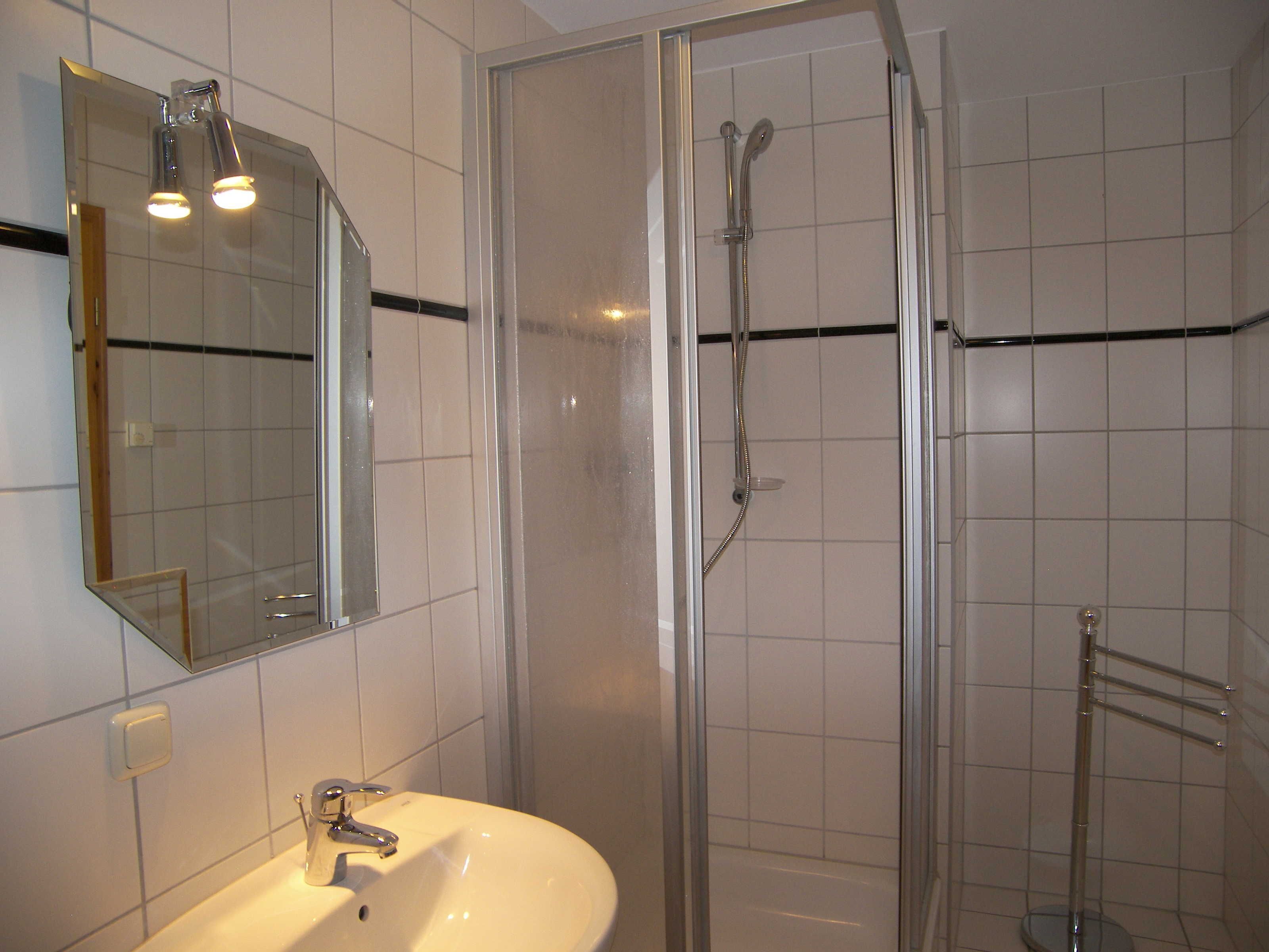 A bathroom with a white sink, a mirror, and a glass-enclosed shower.