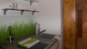 Modernilla designilla varustettu keittiö, jossa on lasihylly, pesuallas ja puuovi.