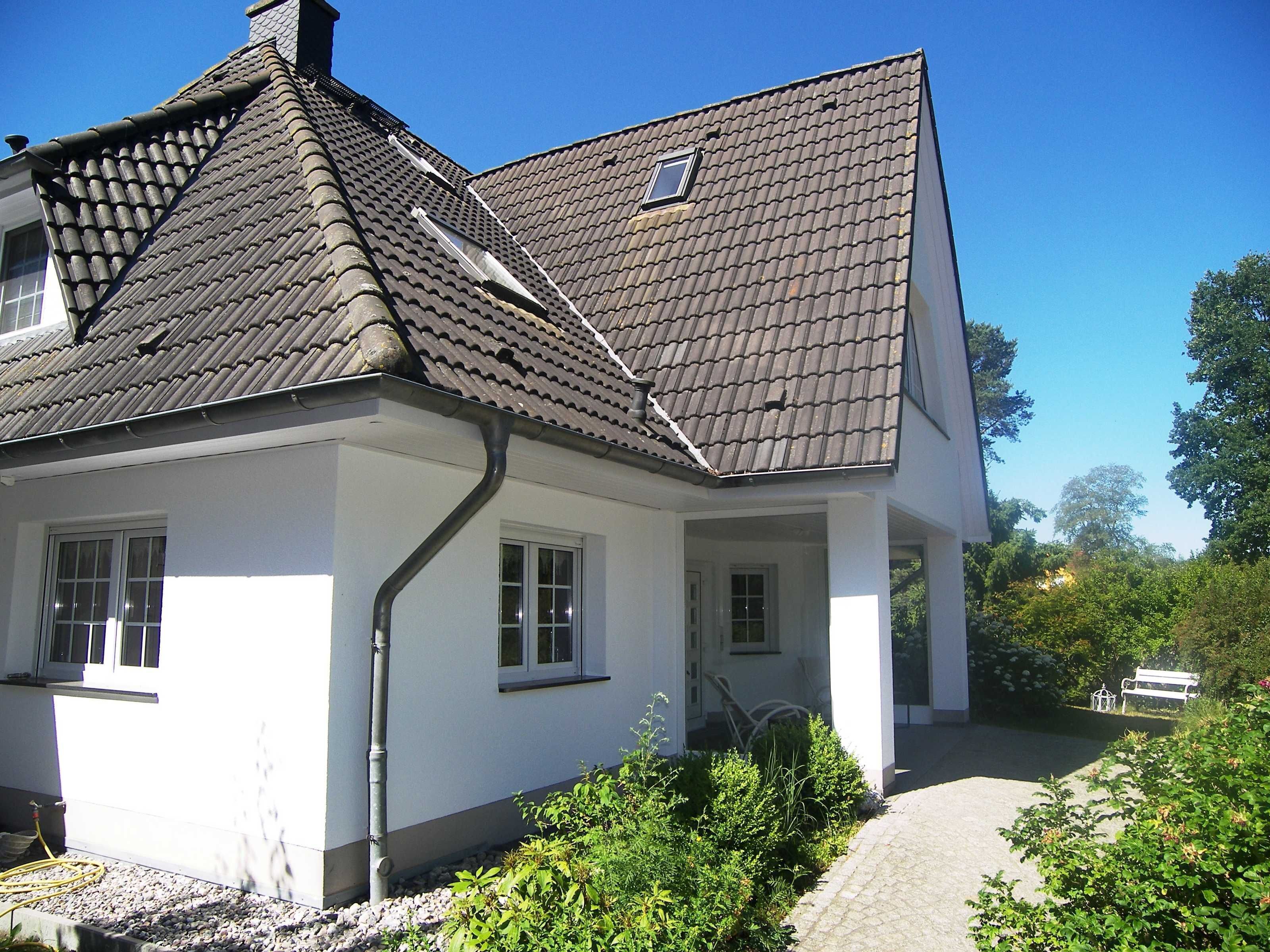 A house with a steeply pitched roof, white exterior walls, and a small window.