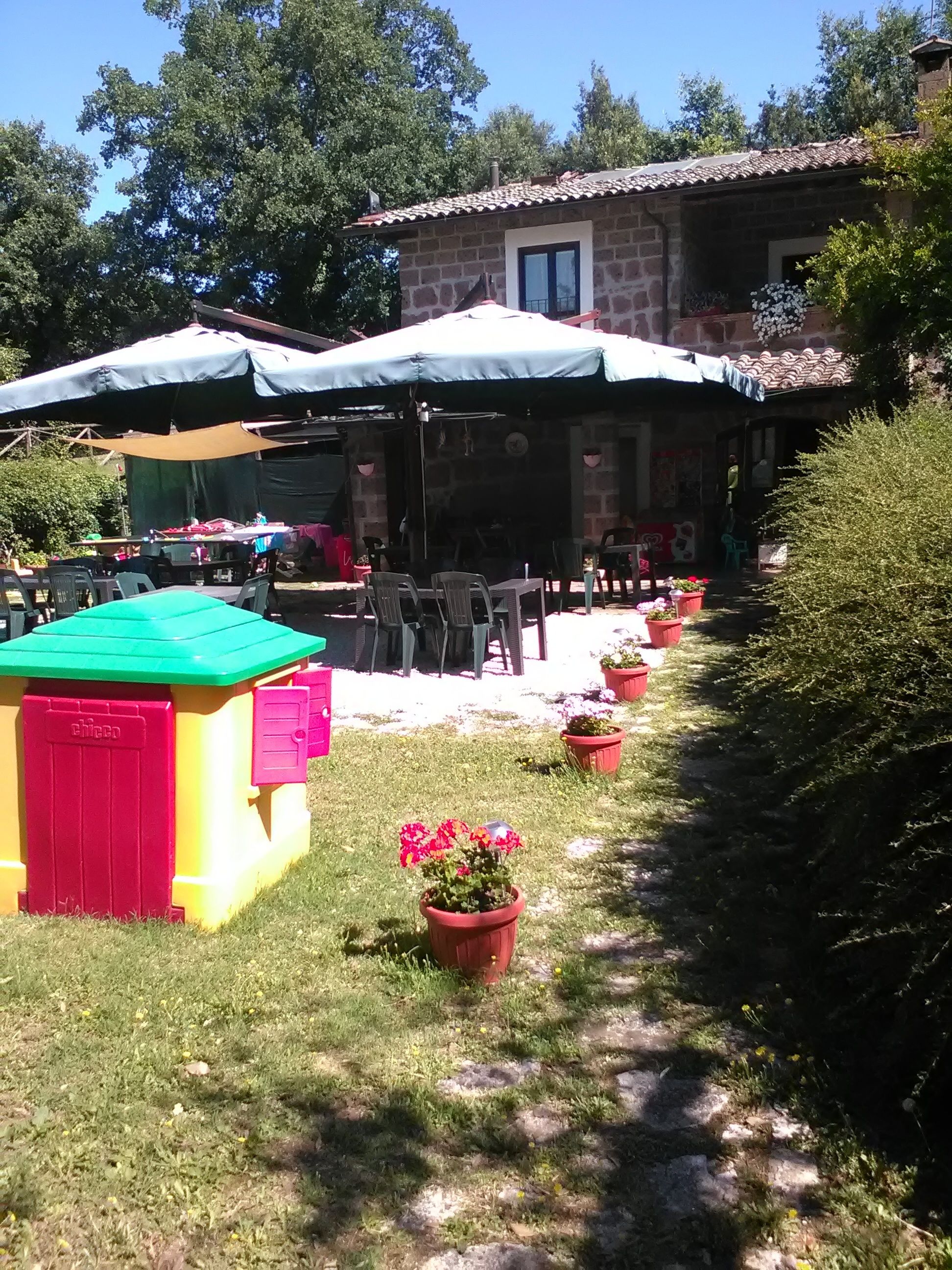 A courtyard with outdoor seating, a stone building, and potted plants.