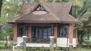 Ein traditionelles Haus mit Ziegeldach, Backsteinwänden und einer Veranda mit Geländer.