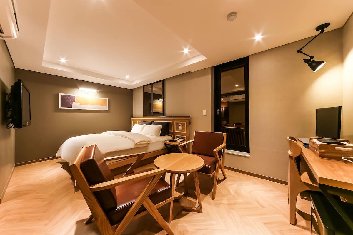 A hotel room with a bed, wooden furniture, a desk, and a mirror.