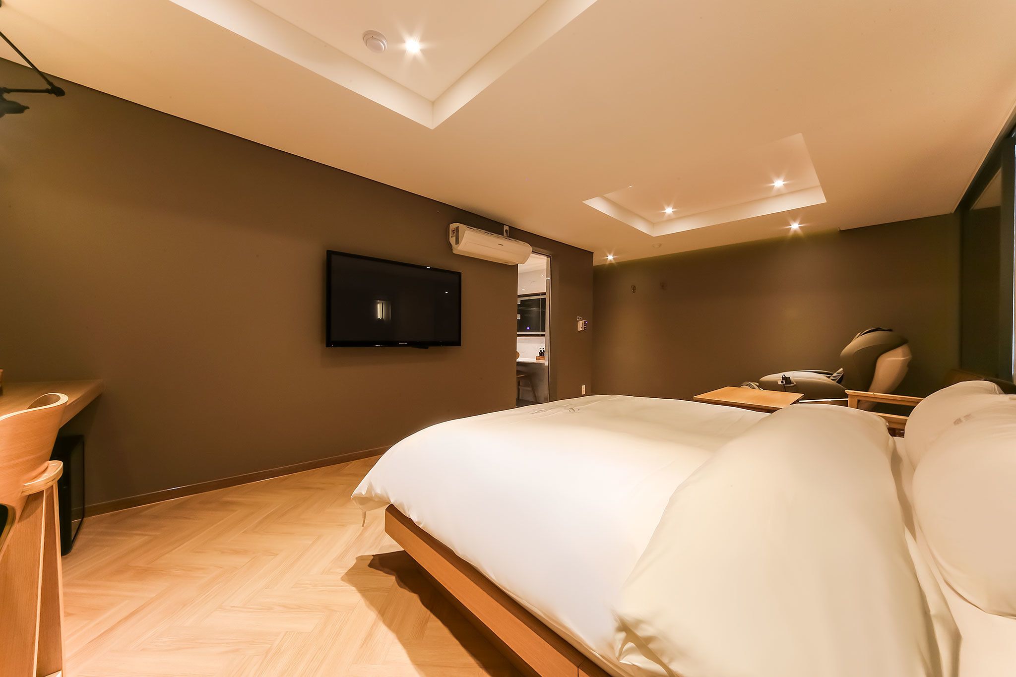 Una habitación de hotel moderna con una cama grande, un escritorio y una televisión montada en la pared.
