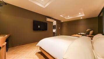 Una habitación de hotel moderna con una cama grande, un escritorio y una televisión montada en la pared.