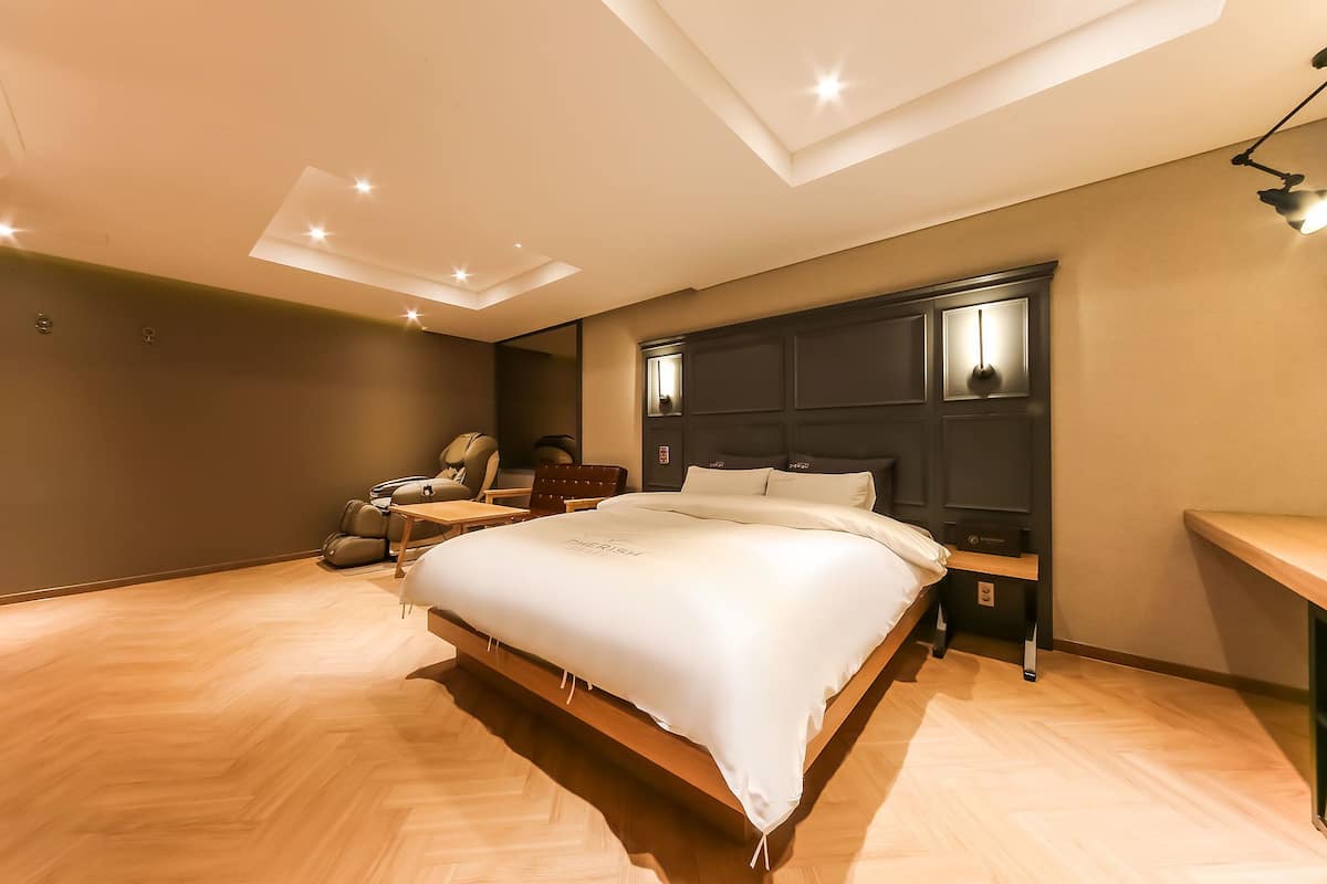 A modern bedroom with a large bed, a desk, and a chair.