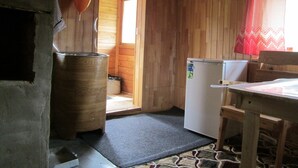 Eine kleine Holzhütte mit einer Küchenzeile, einer Holztür, die nach draußen führt, und einem Fenster mit rotem Vorhang.