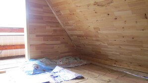 Ein Zimmer mit schrägem Dach, Holzwänden und einem Fenster.
