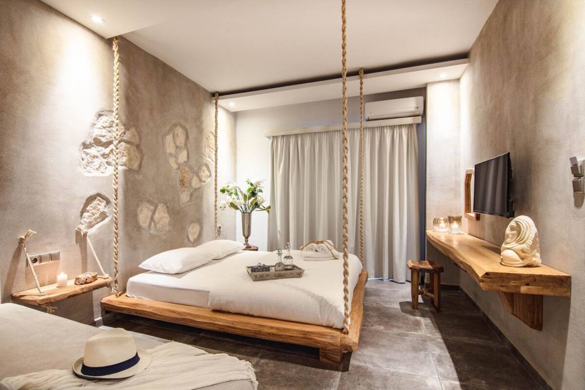 A modern bedroom with a wooden bed, a bedside table with a lamp, a TV, and a decorative wall piece.