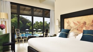 Camera d'albergo con un letto grande, una scrivania con lampada, vista su una piscina e un quadro appeso al muro.