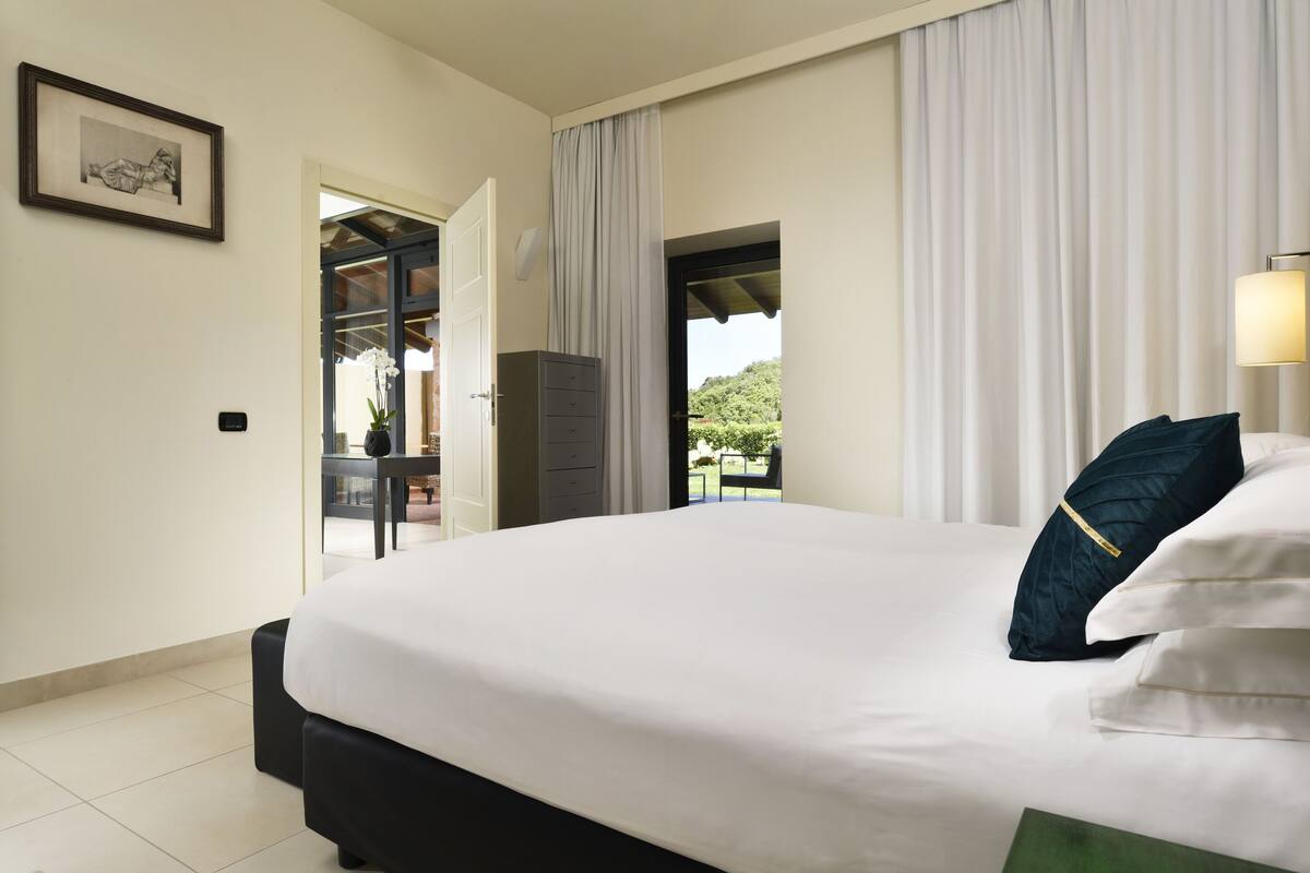 Een hotelkamer met een groot bed, een bureau en uitzicht op groen.