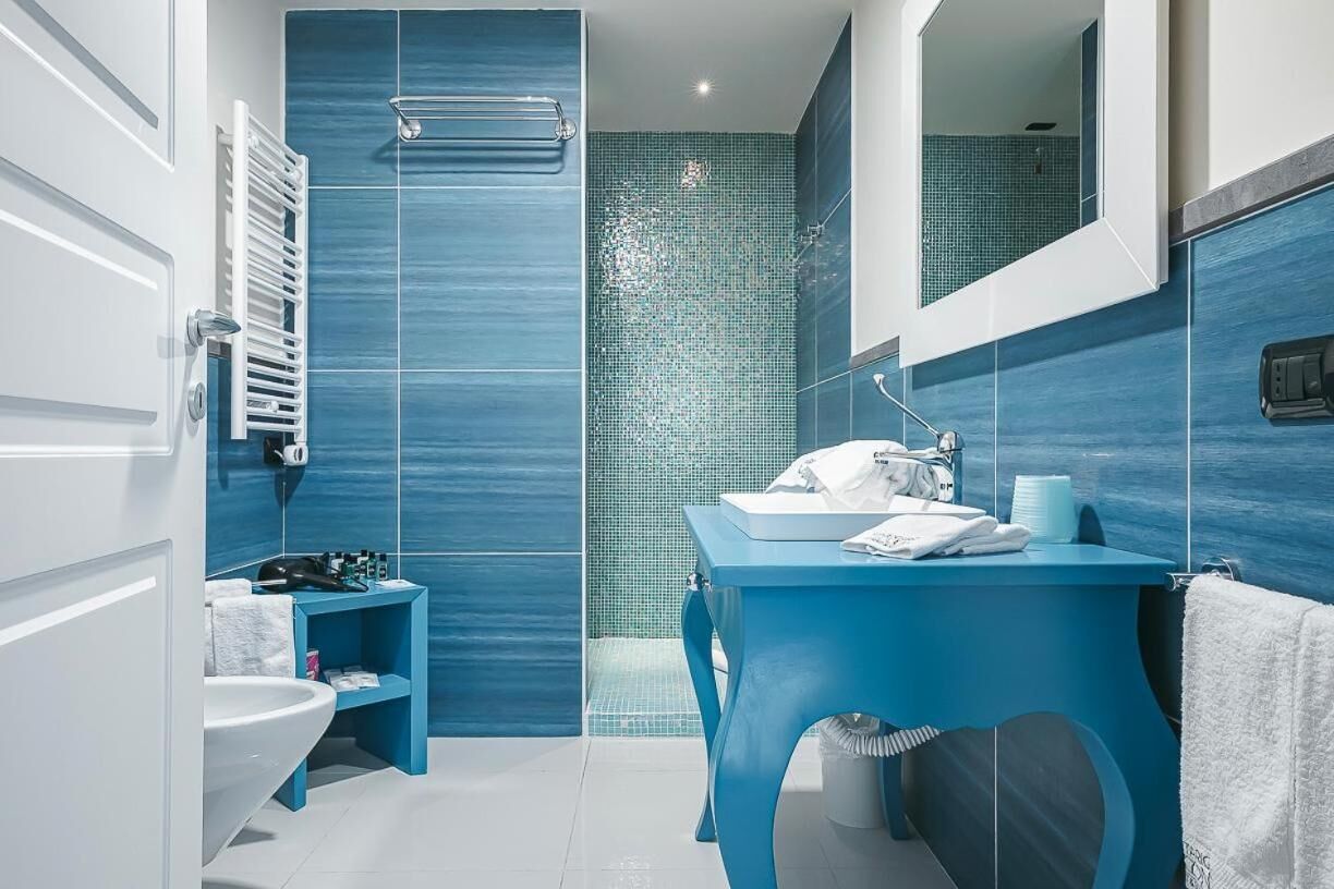 Une salle de bain moderne aux tons bleus, comprenant un lavabo, un miroir et un espace douche.