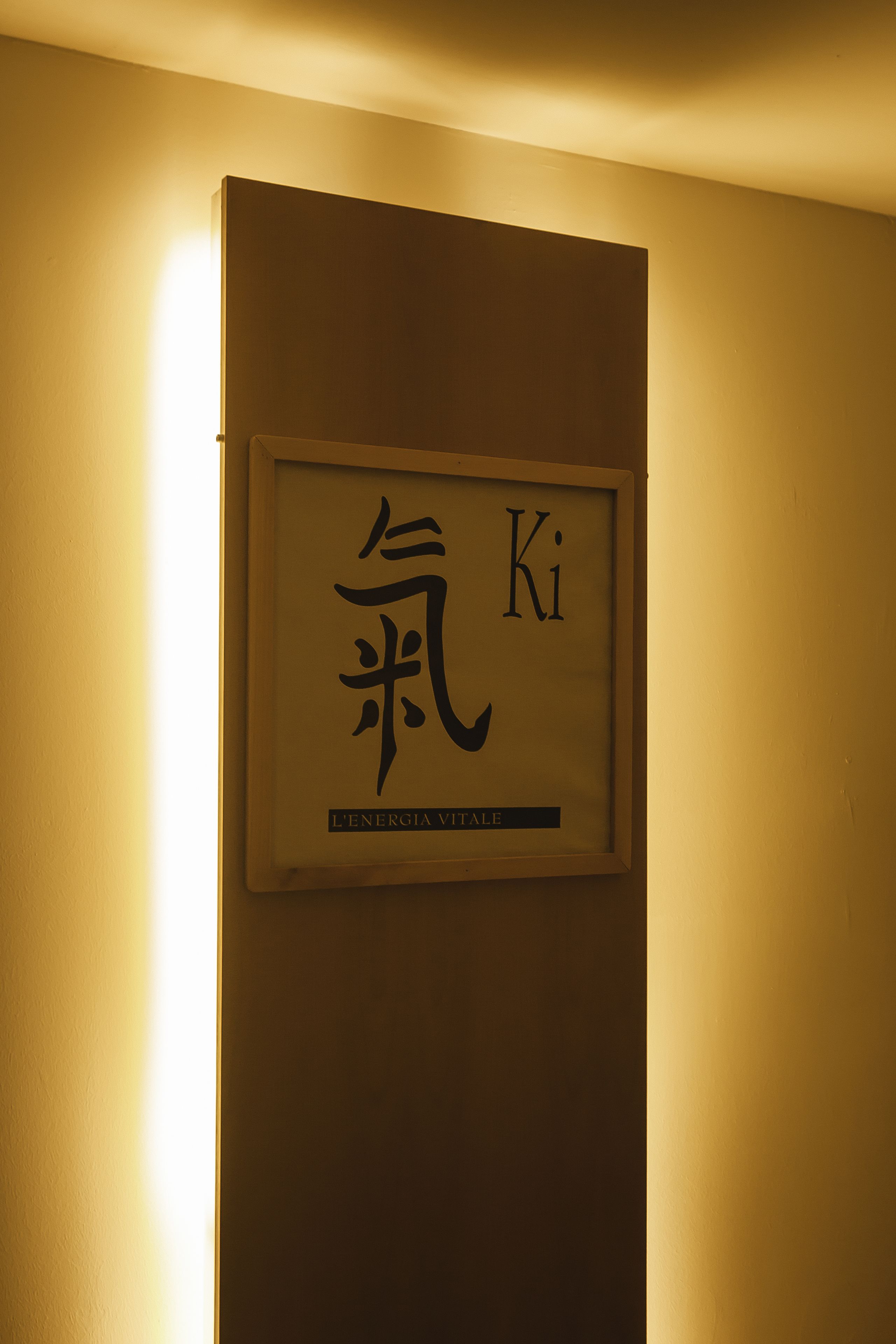A framed sign with Chinese characters and the text "L'ENERGIA VITALE" on a wall.