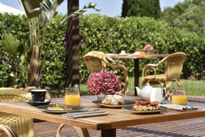 Une table de petit-déjeuner avec des assiettes remplies de nourriture, un vase de fleurs et une théière.