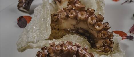 A plate with octopus tentacles and some red sauce.