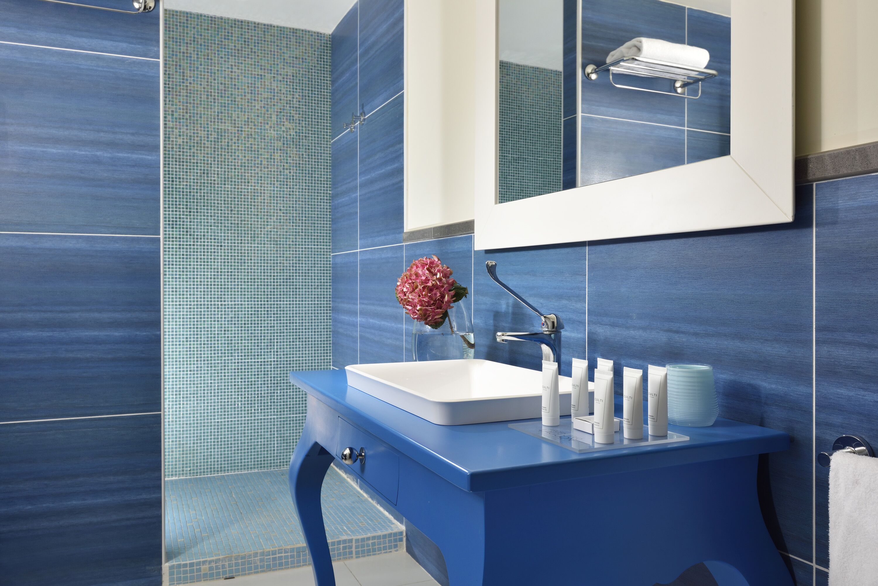 Une salle de bain moderne avec un meuble-lavabo bleu, un lavabo blanc et un miroir au-dessus.