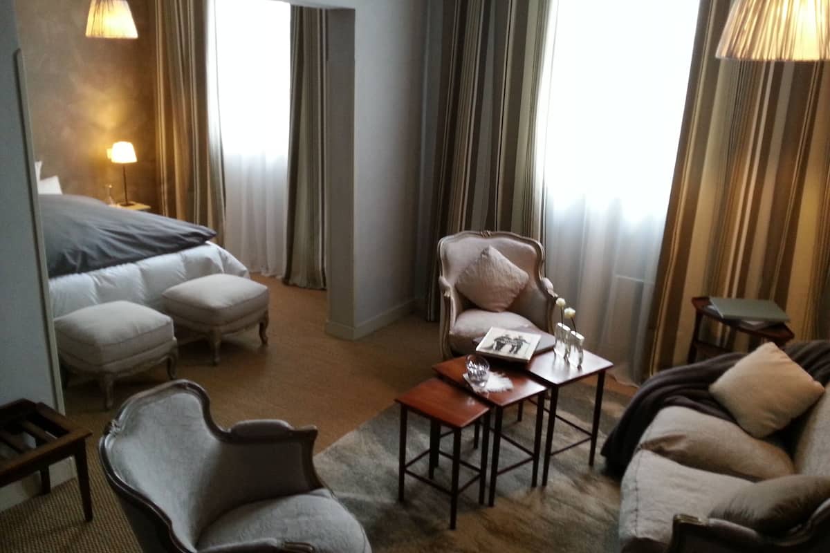 Una habitación de hotel con una cama, dos sillones, un sofá, una mesita y una lámpara.