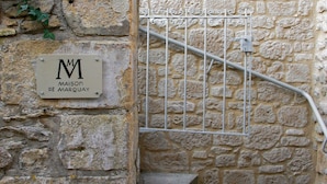 A stone staircase leading to a room with a metal gate and a sign reading "MAISON DE MARQUAY". - Maison de Marquay (Marquay)