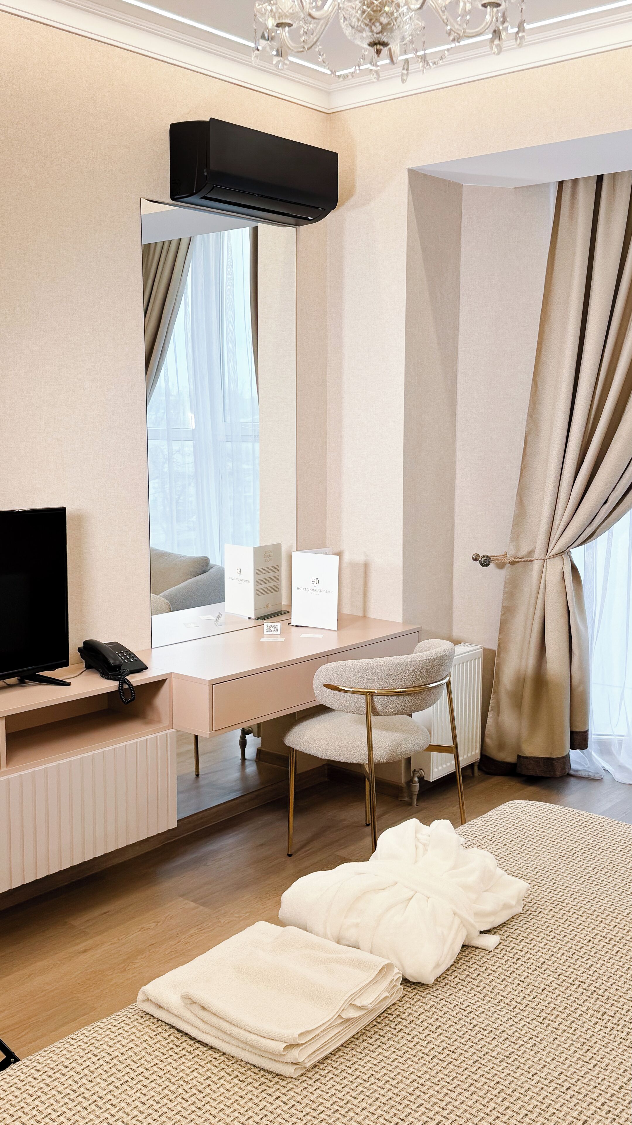 A hotel room with a large bed, a desk with a chair, a television, a telephone, and a radiator.