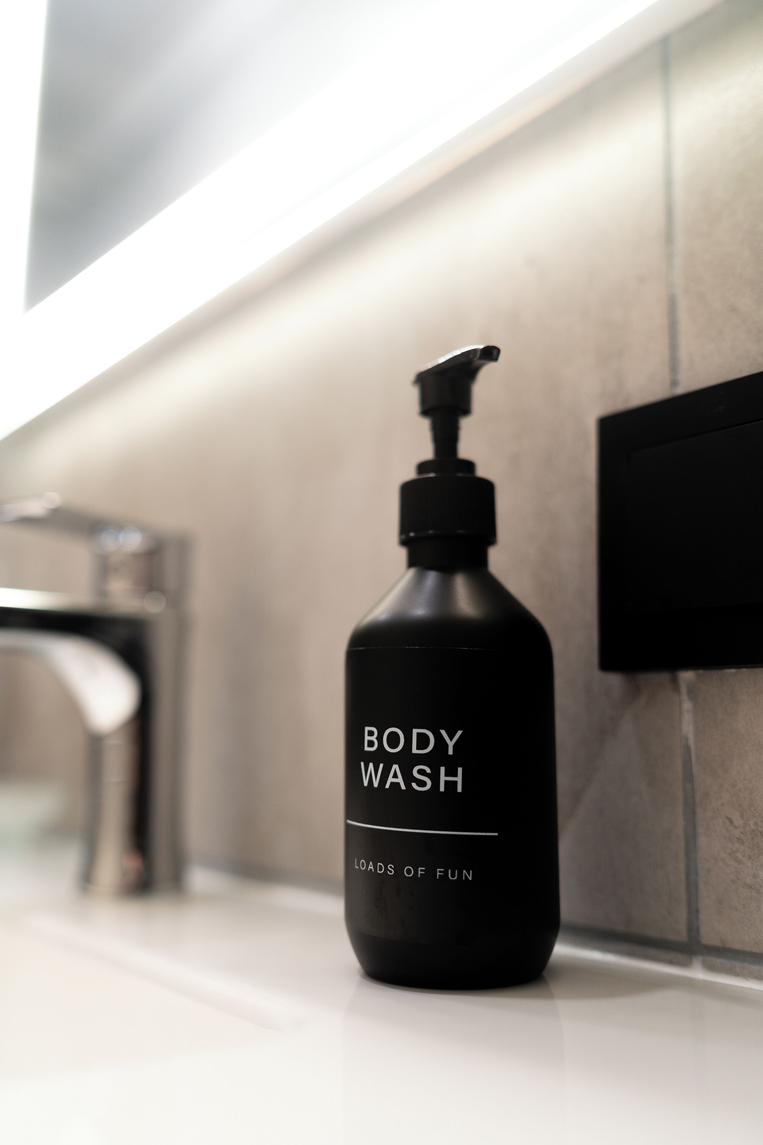 A black body wash bottle with a pump dispenser on a bathroom counter.