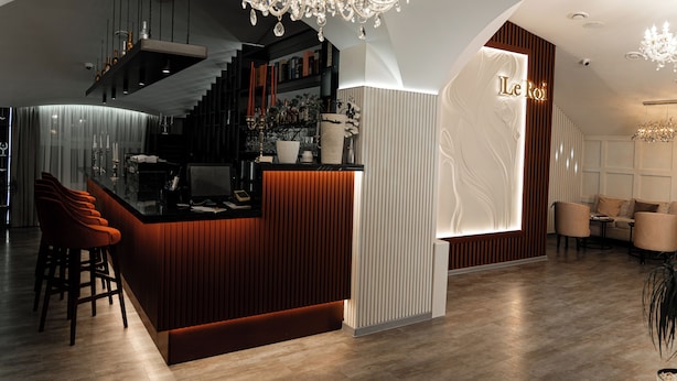 Un área de bar moderna con mostrador de madera, taburetes y una lámpara de araña.