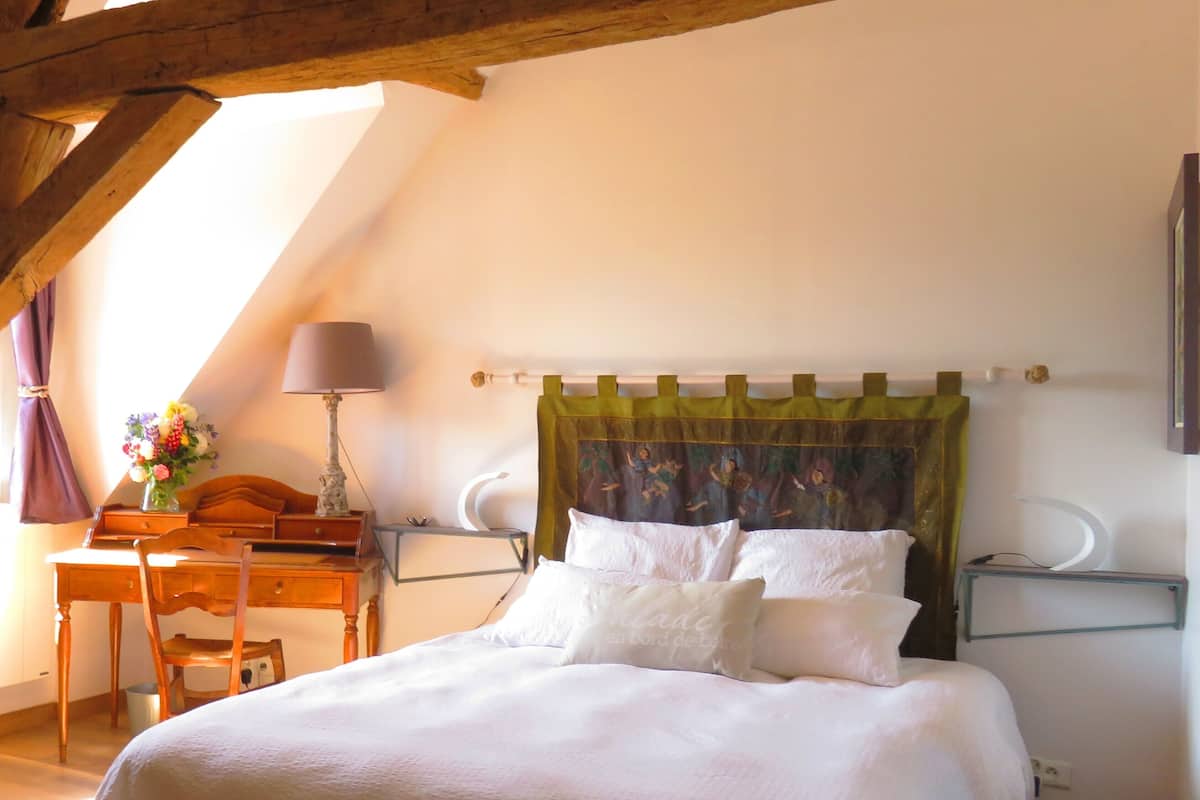 Un dormitorio con cama, escritorio, silla, lámpara y ventana.