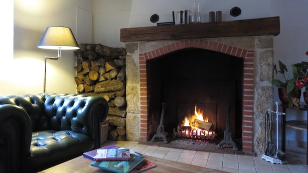 Una sala de estar acogedora con una chimenea de piedra, un sofá de cuero y una mesa de centro con libros.