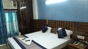 A hotel room with a bed, a nightstand, a telephone, and an air conditioning unit. - Hotel Jhanvi Palace (New Delhi)