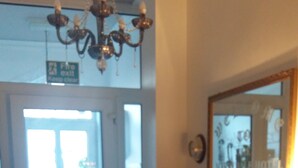 Eine Hotelhalle mit einem gemusterten Boden, einer Chandelüstere, einem Spiegel und einer Lampe auf einem Tisch.
