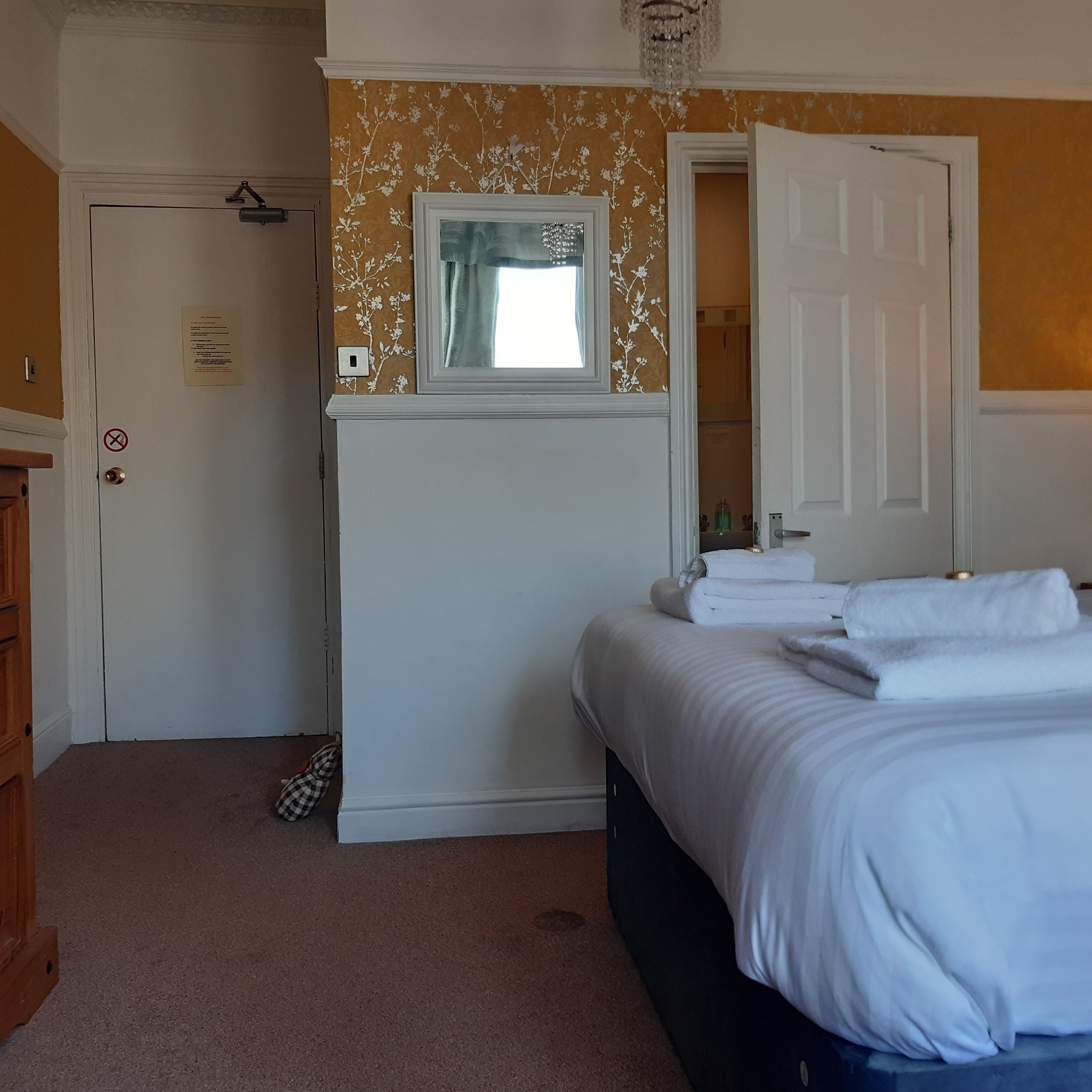 A bedroom with a bed, a dresser, a mirror, and a door.