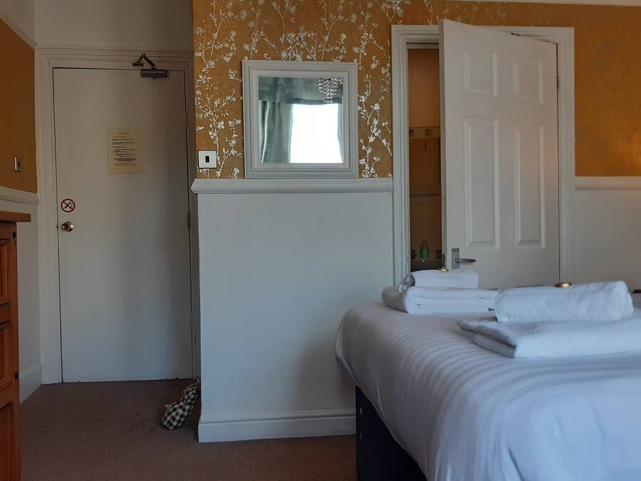 A bedroom with a bed, a dresser, a mirror, and a door.
