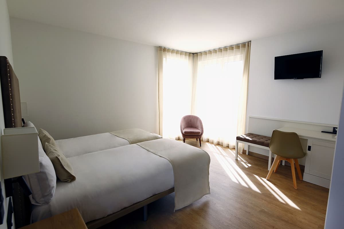 A hotel room with a bed, a desk, a chair, and a TV.