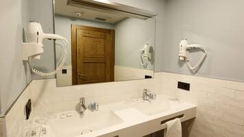 A bathroom with two sinks, a mirror, a hairdryer, and a towel rack.