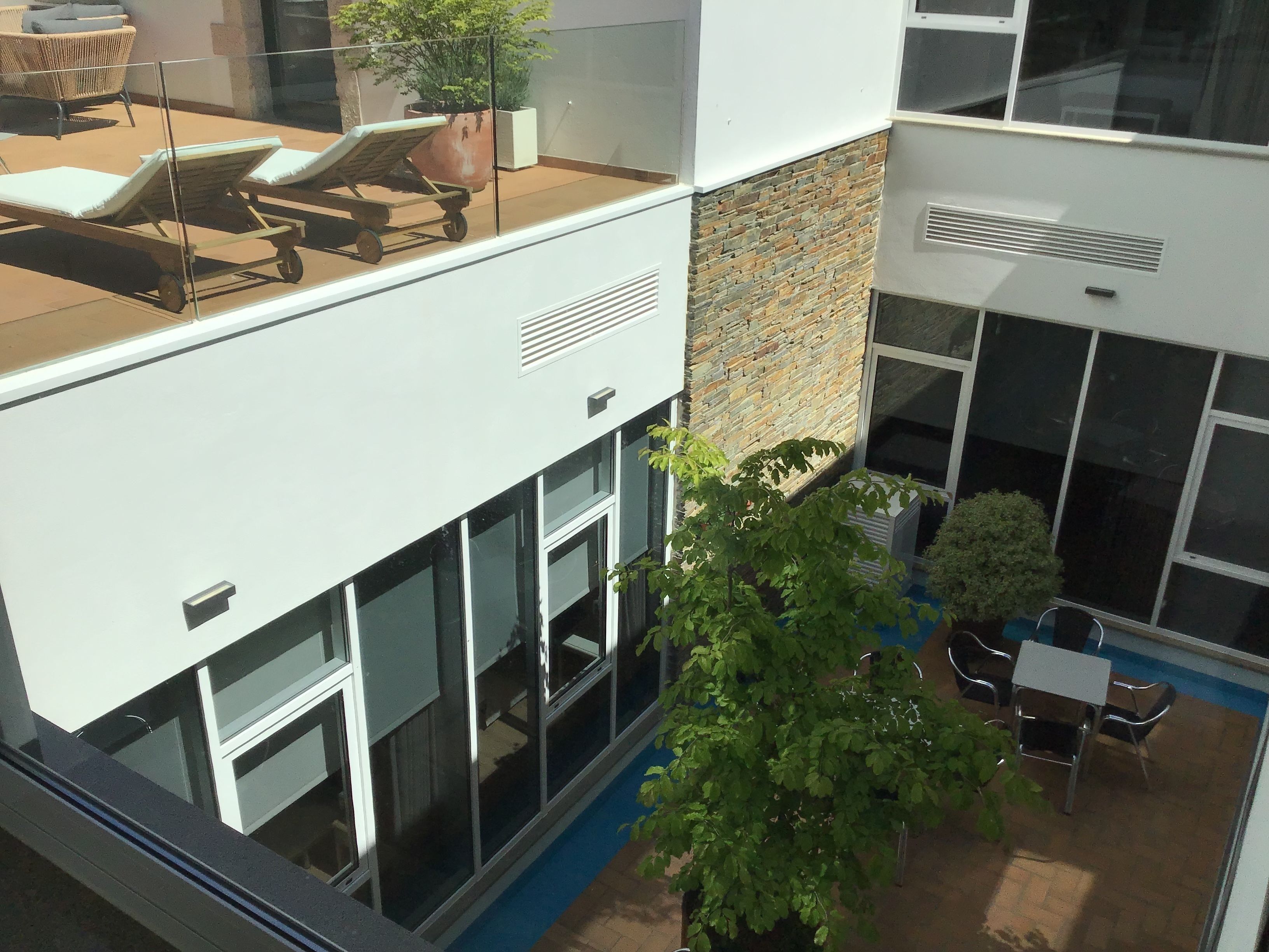 A modern building with a rooftop lounge area, large windows, and a stone facade.