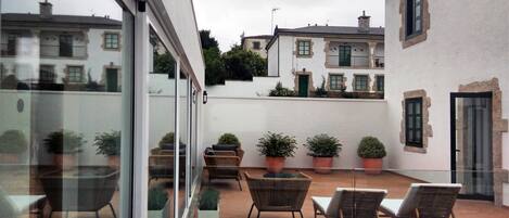 A courtyard with outdoor seating, potted plants, and a view of neighboring buildings.