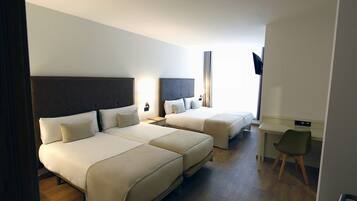 Een hotelkamer met twee bedden, een bureau en een stoel.