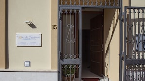 A building entrance with a metal gate, a sign with contact information, and a potted plant. - Sole di Trapani (Trapani)