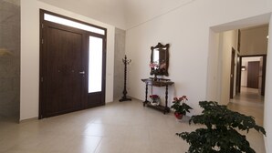 A spacious hallway with a large wooden door, a wall-mounted mirror, and a potted plant. - Sole di Trapani (Trapani)