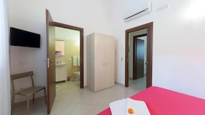 A room with a bed, a chair, a wardrobe, a TV, and a bathroom visible through an open door. - Sole di Trapani (Trapani)